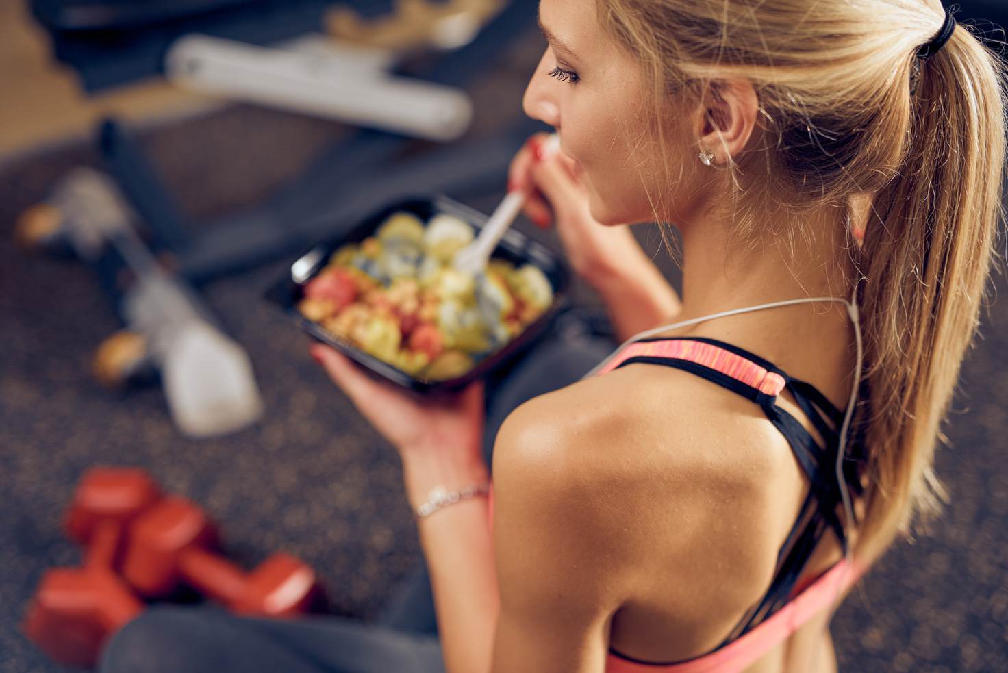 Top view of woman eating healthy food in a gym.