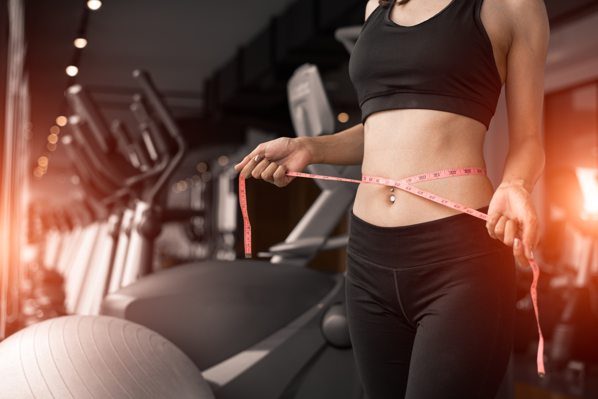 Sporty woman using waist tape line in fitness gym sport club training center near window with condominium background. Lifestyle of people workout exercise sport activity. Diet and weight loss theme.